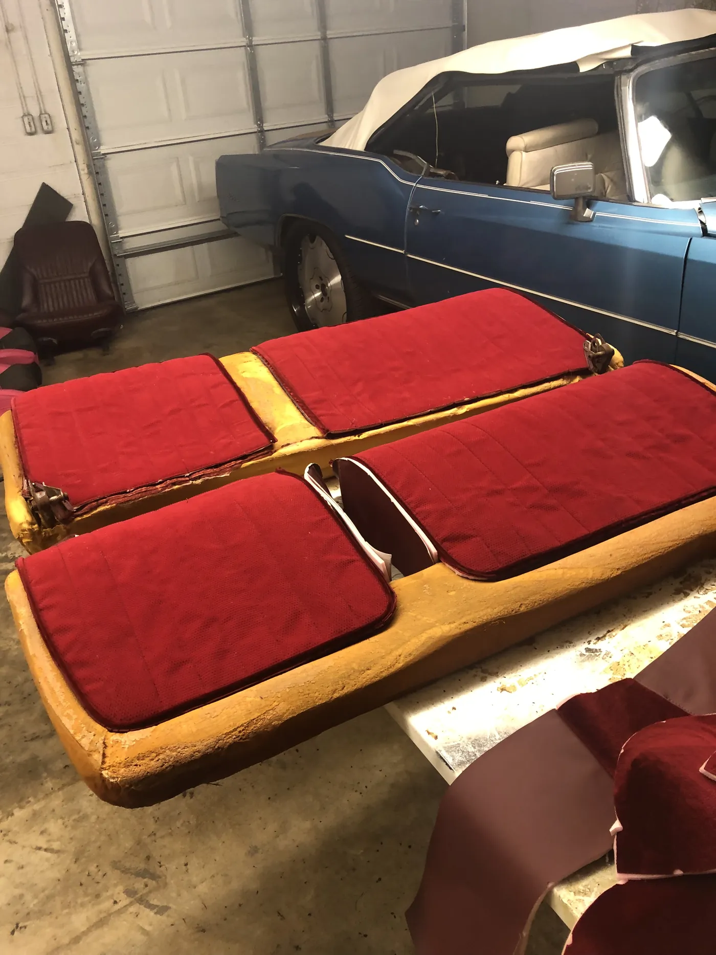 A red bench seat in pieces on the workbench with the old covers off