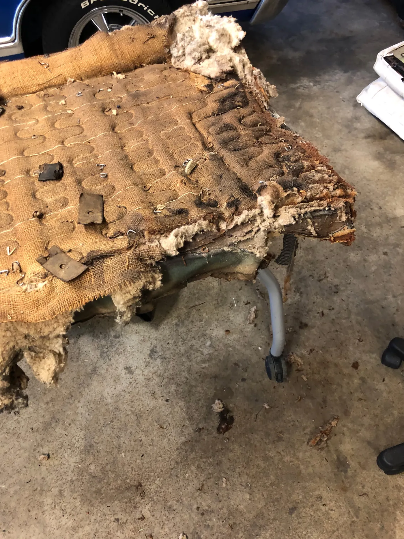 A seat stripped back to its frame, the rotted burlap and old padding hanging off the springs