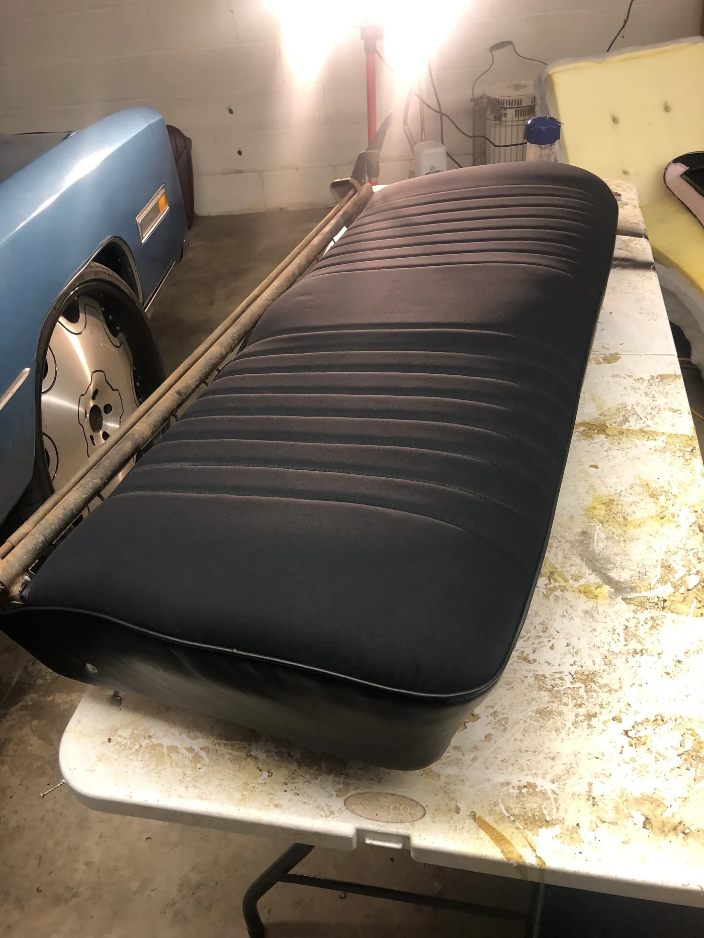 A bench seat recovered in black on the shop table, the new panels pulled taut over the rebuilt base