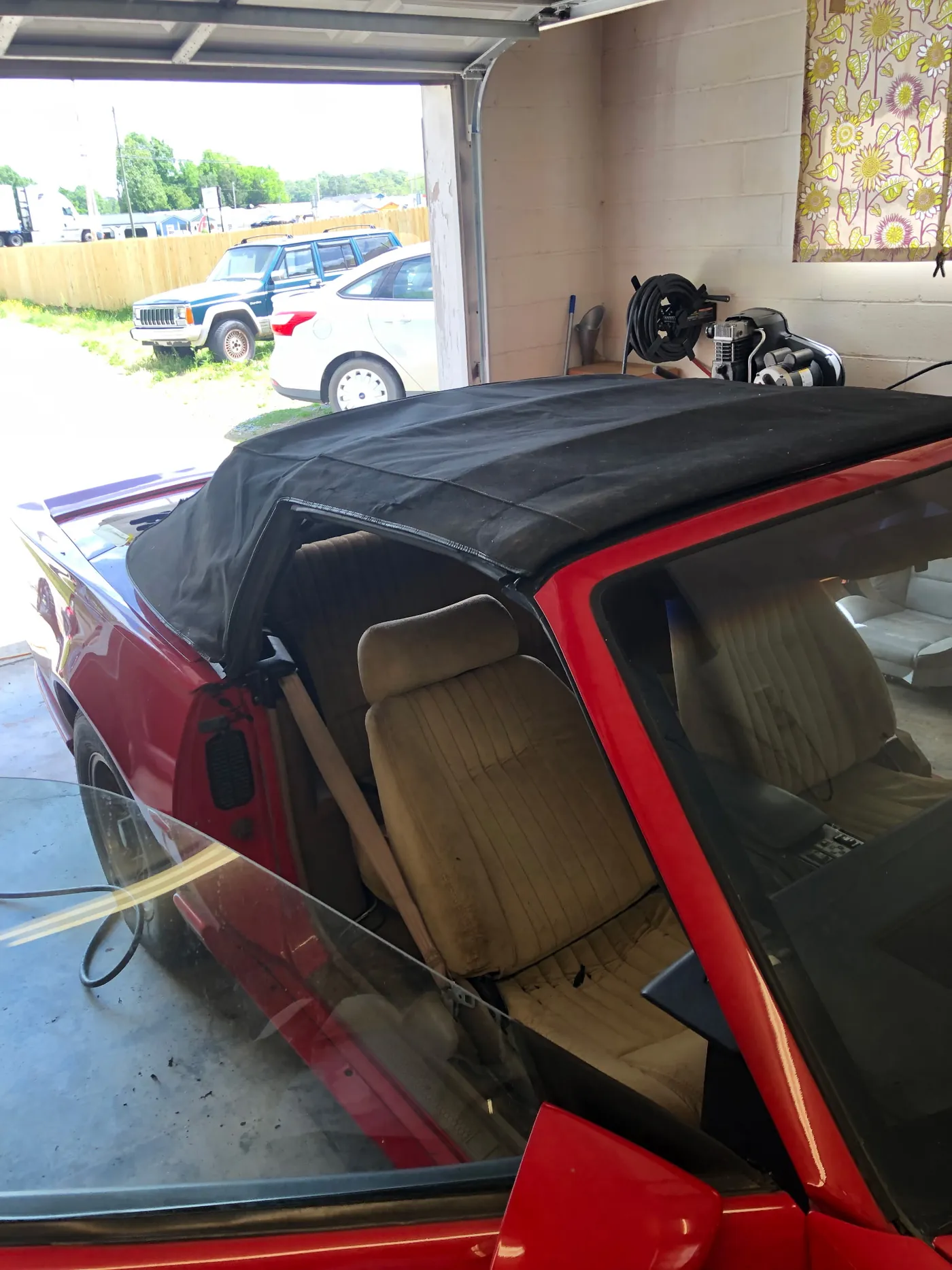 A red convertible in the bay with the top out and the frame exposed