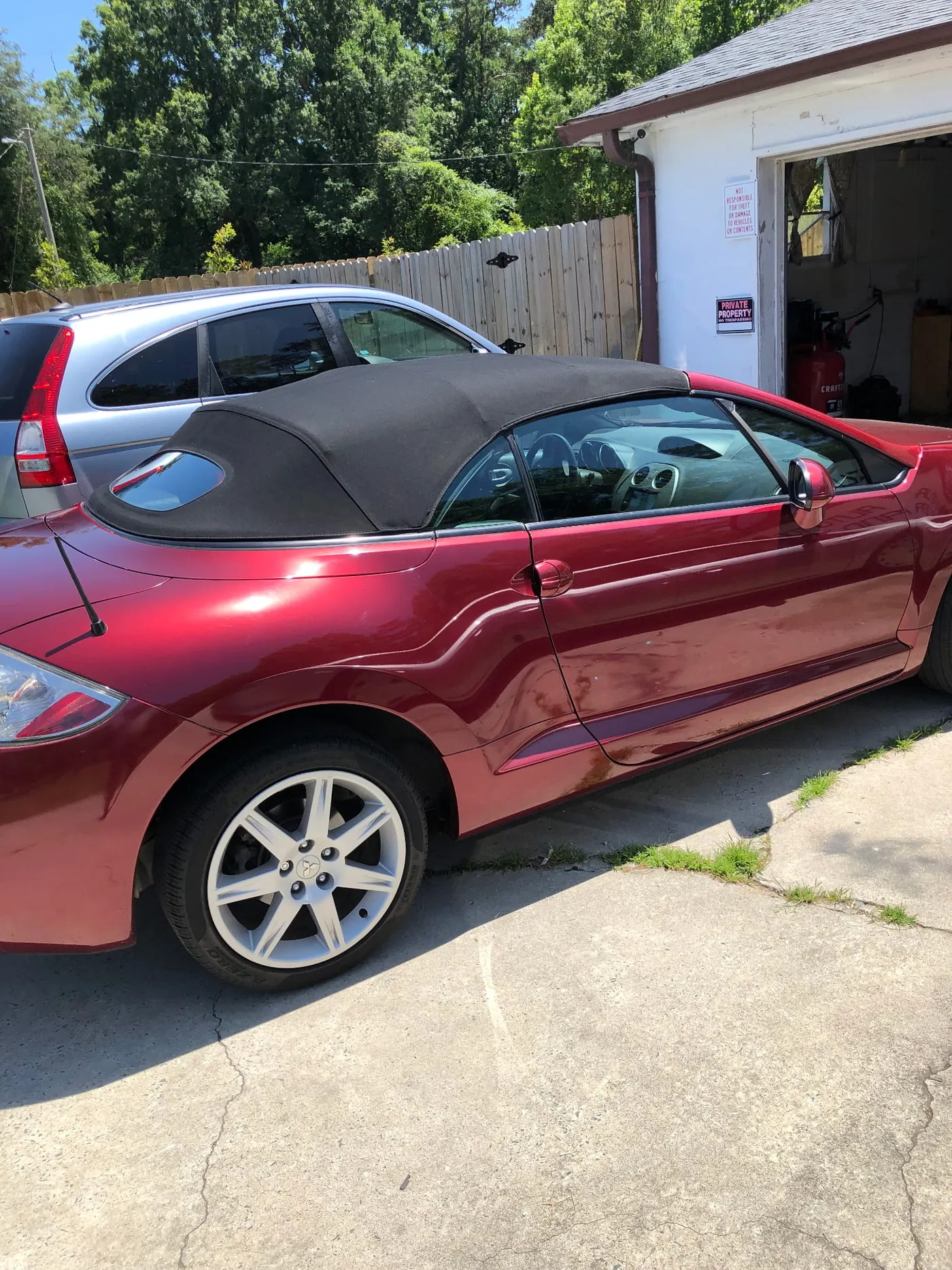 A burgundy convertible with a black top on the driveway