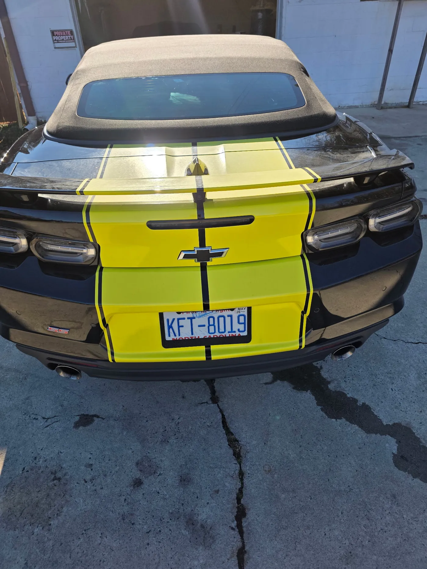 The yellow-striped Camaro from the rear, tan top fitted