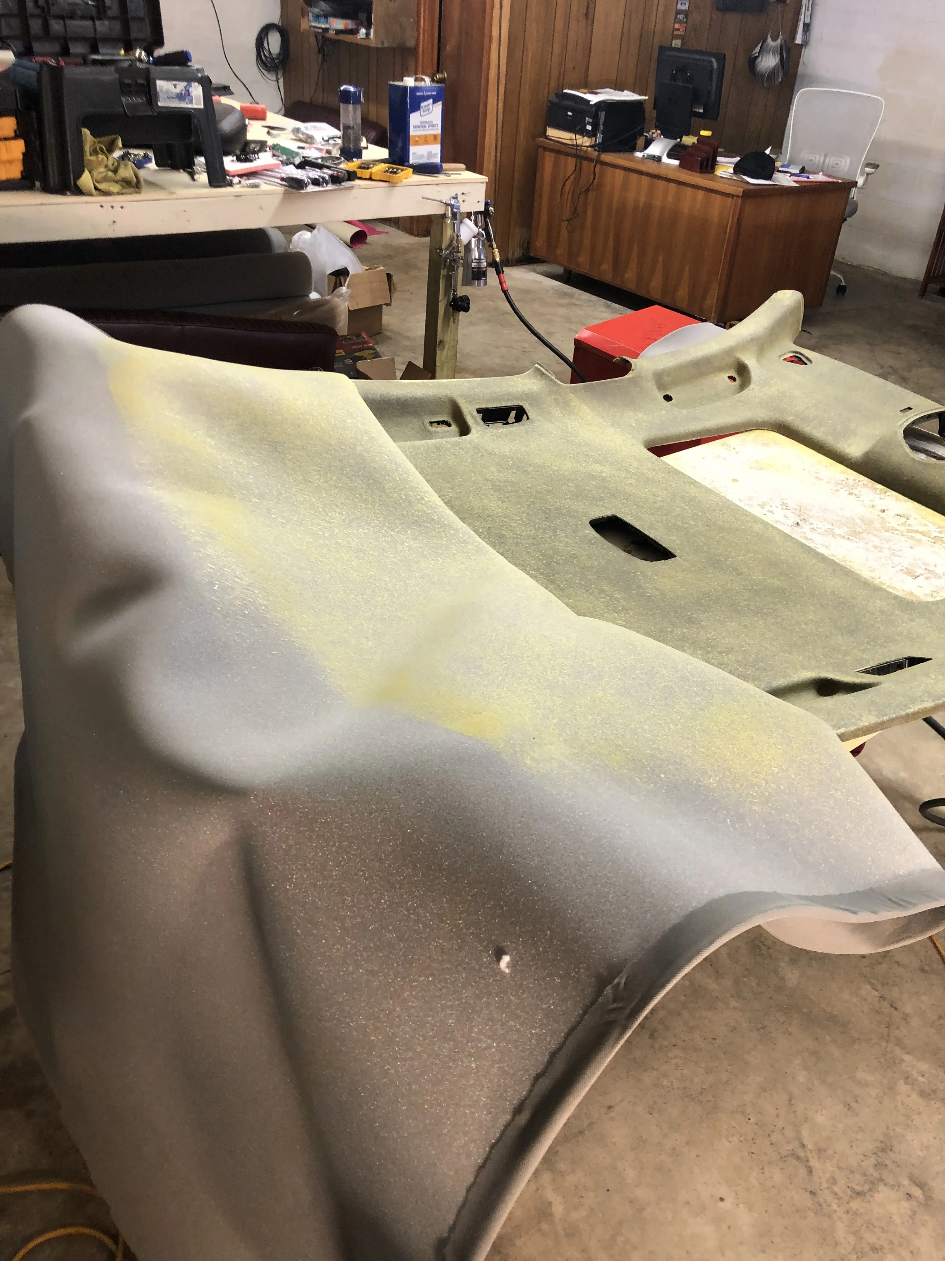 New grey foam-backed fabric being laid onto the stripped headliner board