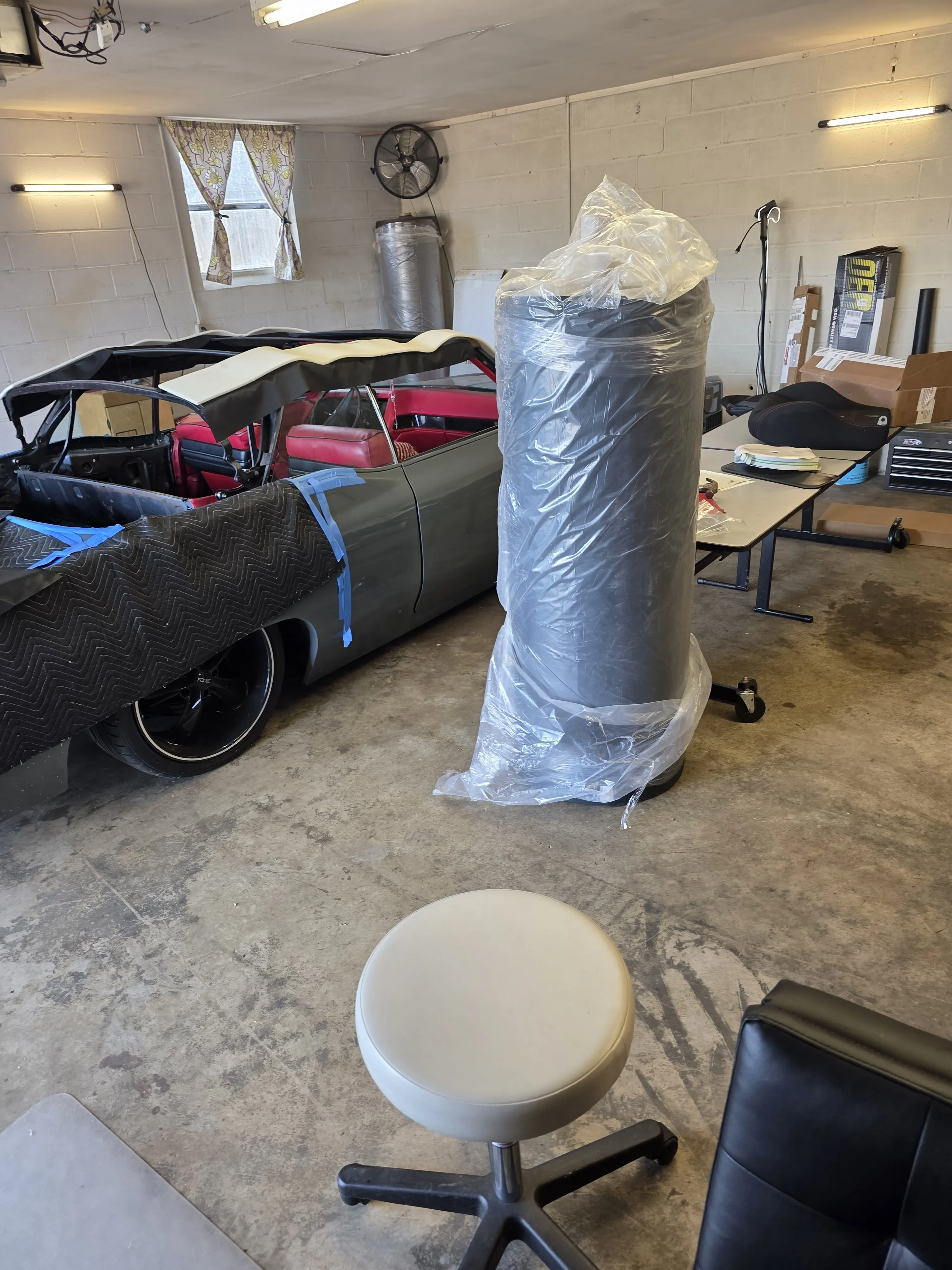 A convertible in the shop with the benches behind it