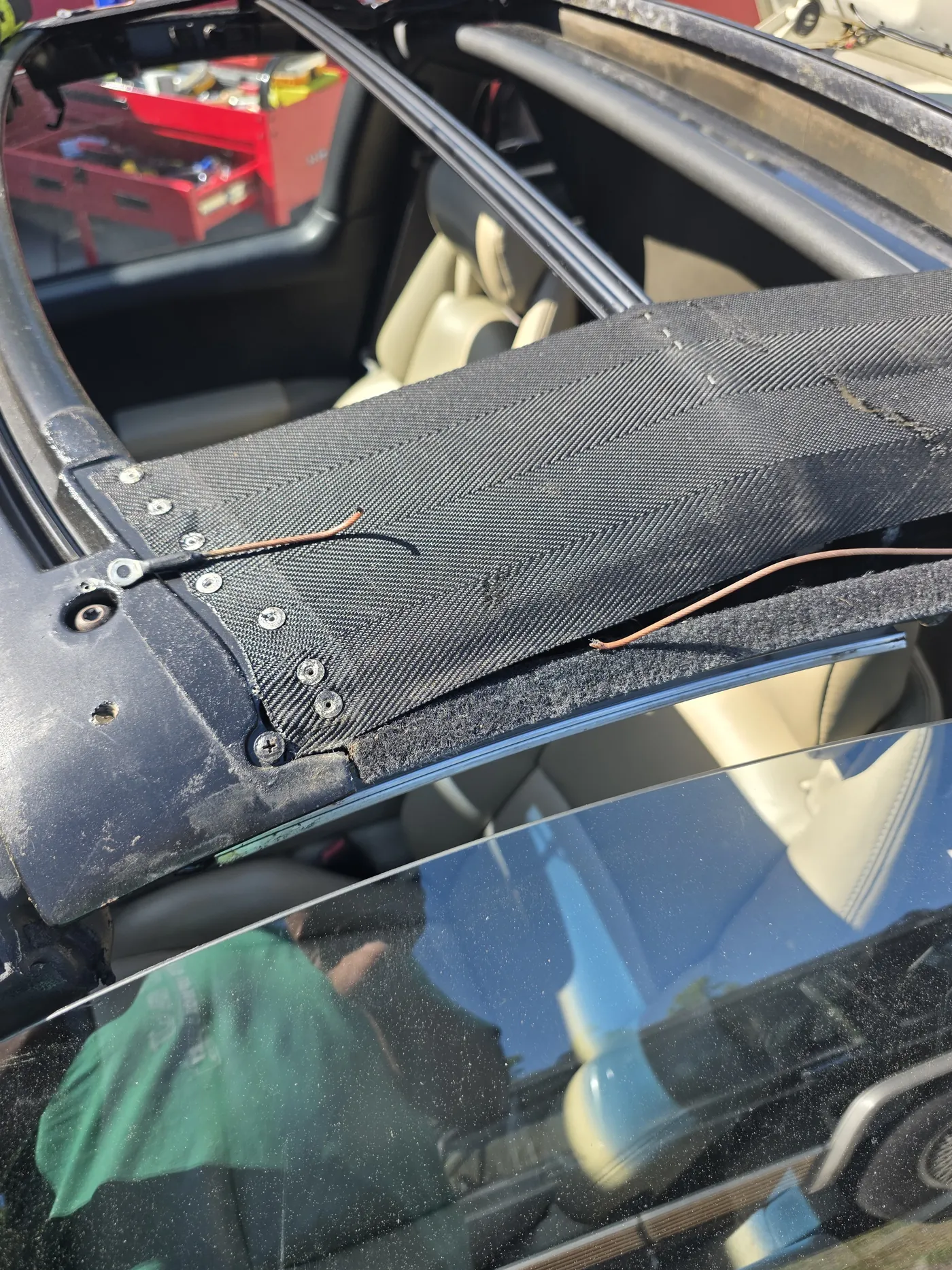 A sunroof assembly lifted out of the car, its frame, shade and fixings exposed