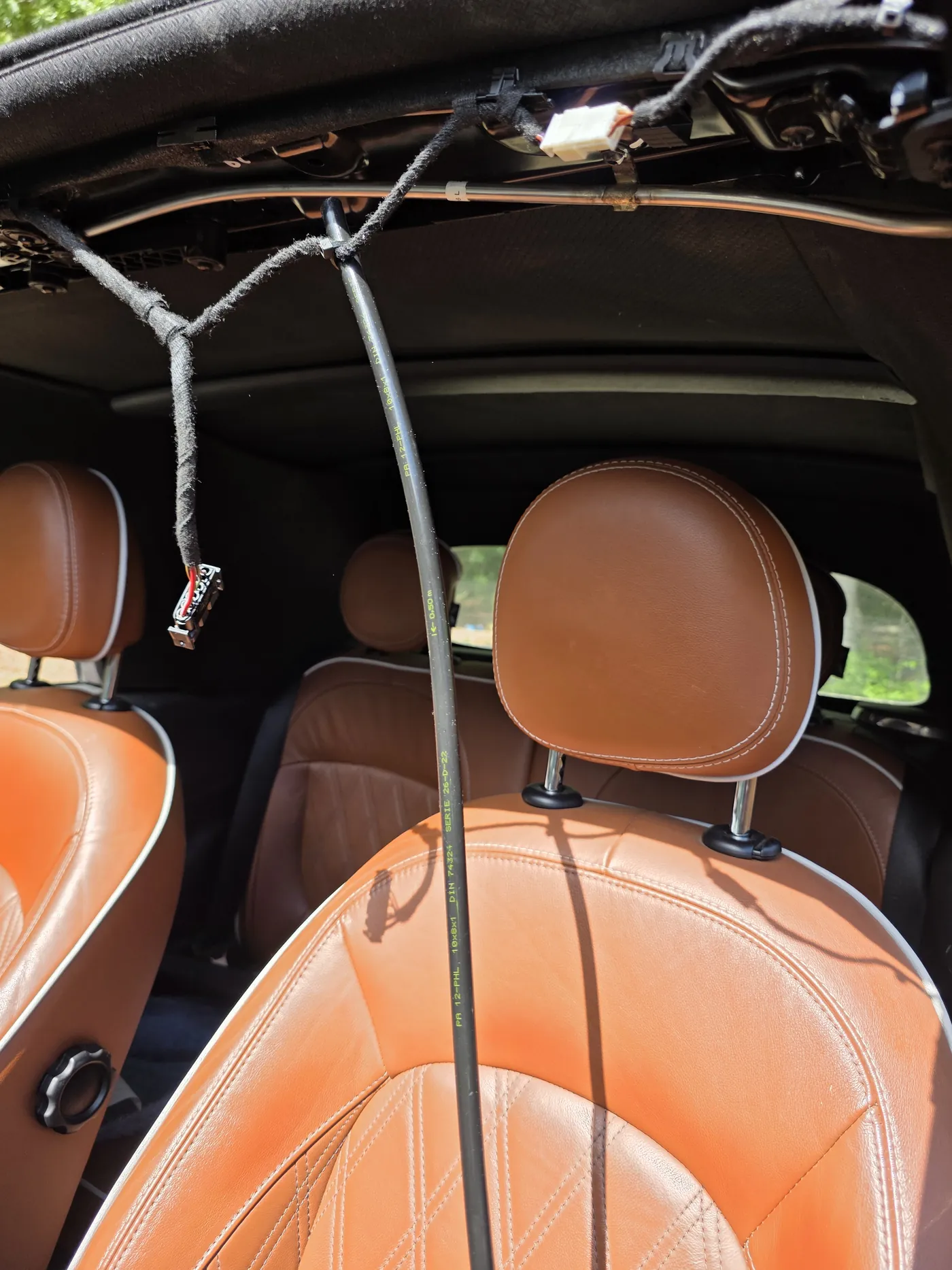 Looking up through the roof opening from inside the car with the sunroof unit out and its cable hanging free